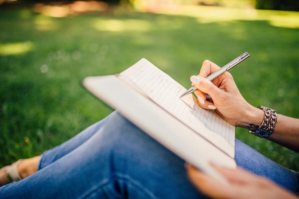 hire essay writers UK Hire essay writers UK - student writing in notebook outdoors