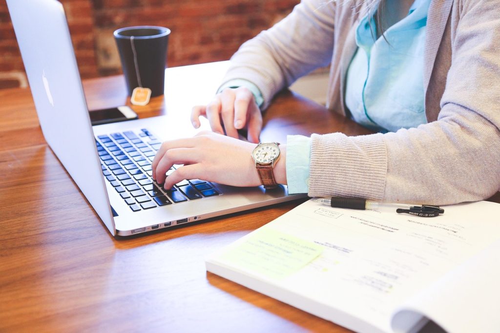 Mastering assignment writing — student typing on a laptop with notes and highlighters