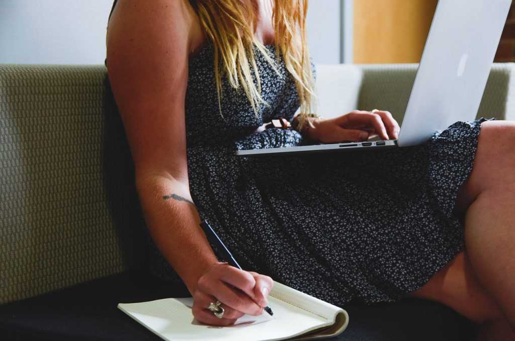 How our assignment writing help UK works – student taking notes with a laptop