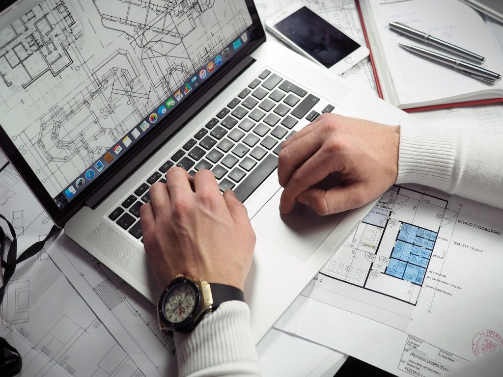 civil engineering project support Civil Engineering Project Support: Student engineer working on a laptop with blueprints and structural drawings
