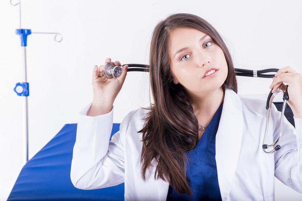 Nursing Assignment Help UK – student nurse in scrubs with stethoscope on ward bed